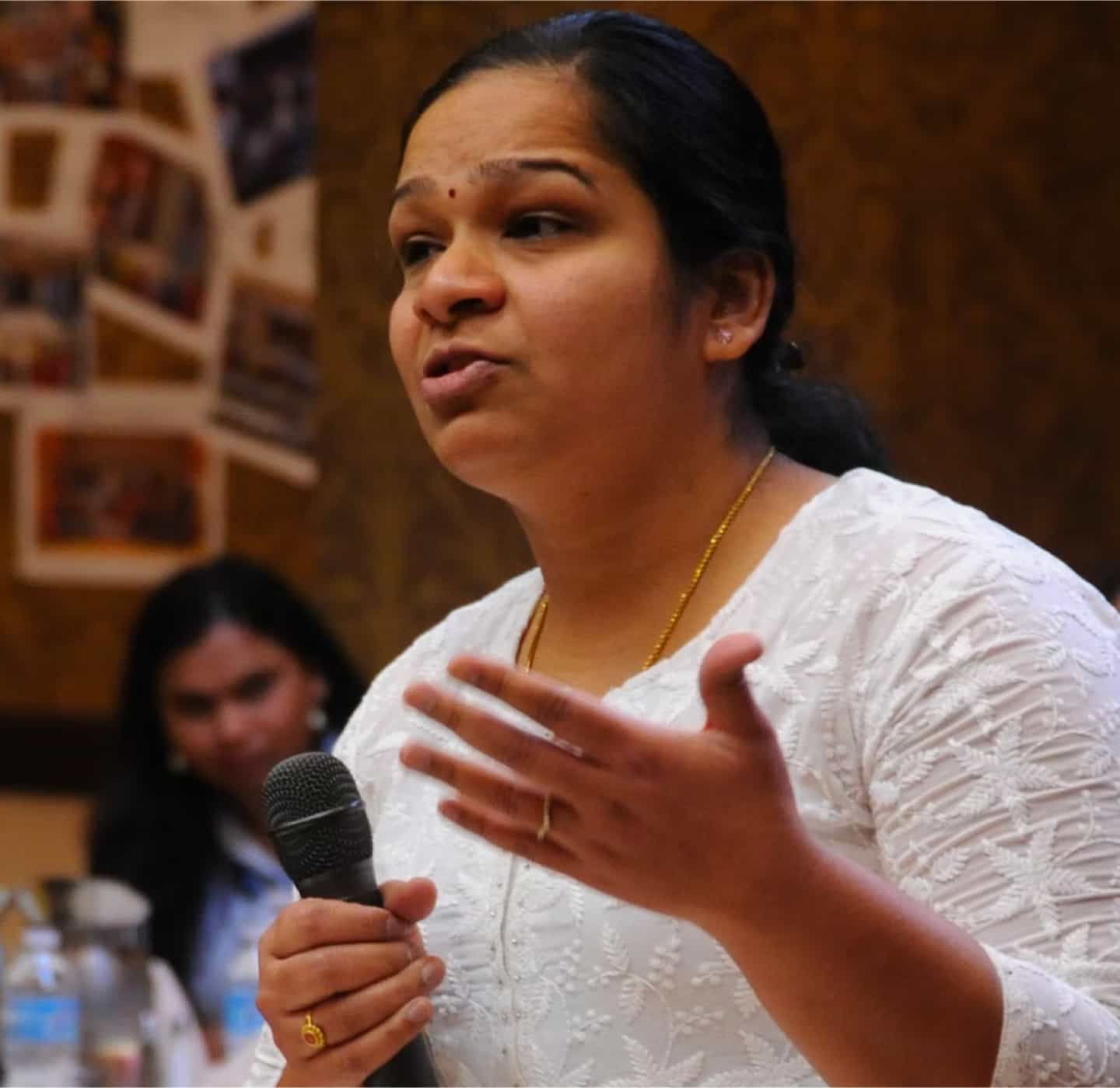 A woman holding a microphone speaks passionately in a town hall