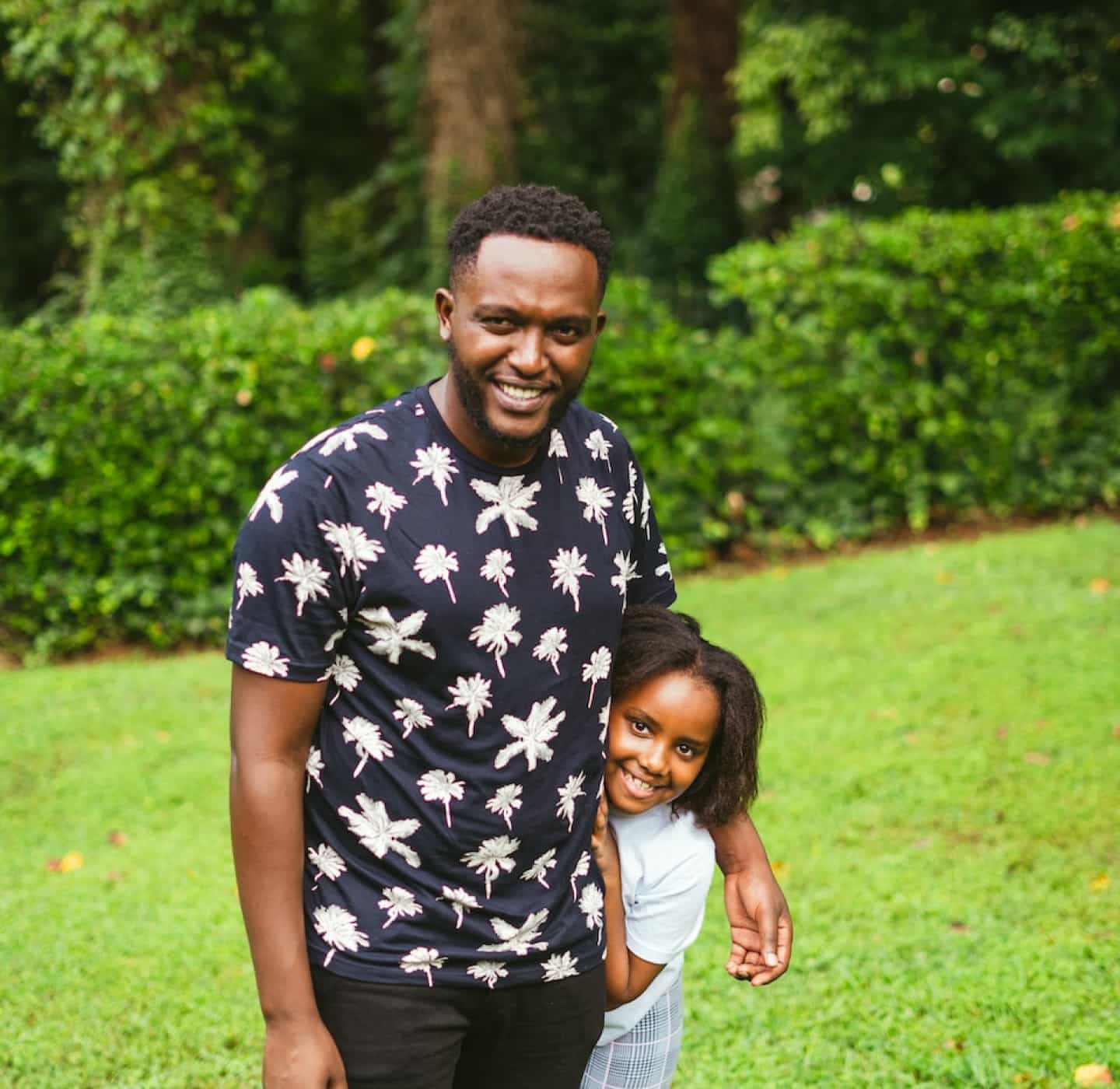 An adult and a child smile at the camera and hug each other