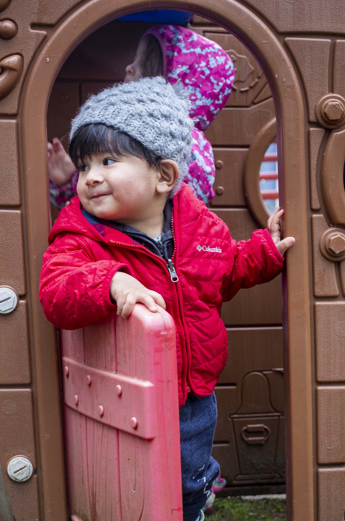 Child in red jacket playing outside.