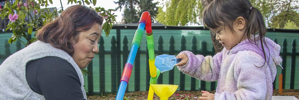 child care provider plays with child outside