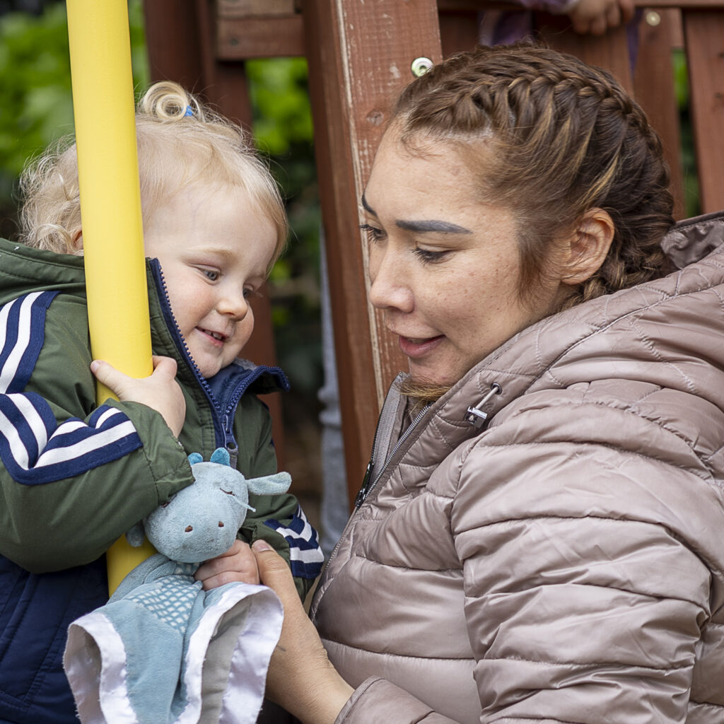 a child care provider plays with child on playground